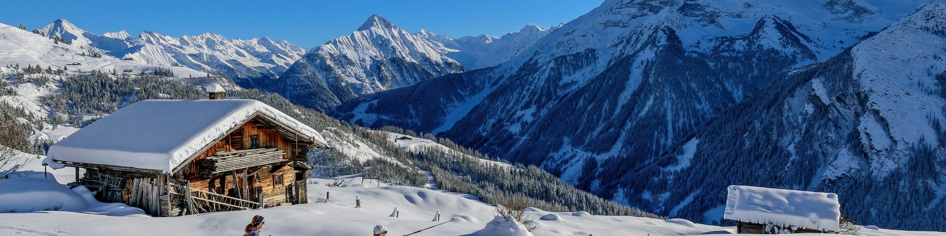 A snowy mountain landscape with a wooden cabin and a ski slope.