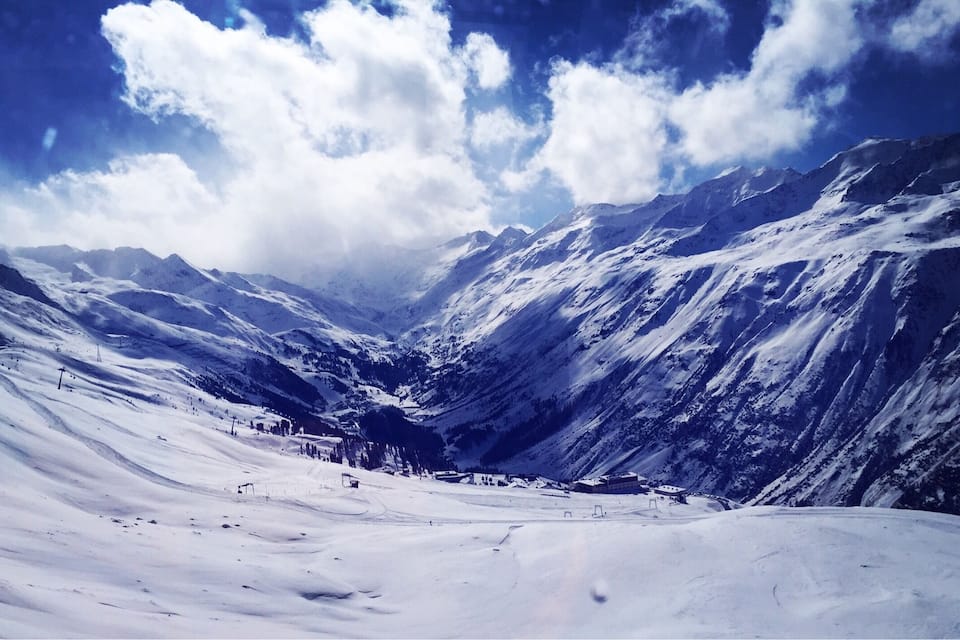 Ein verschneites Gebirge mit einem Tal und wolkenlosem Himmel.