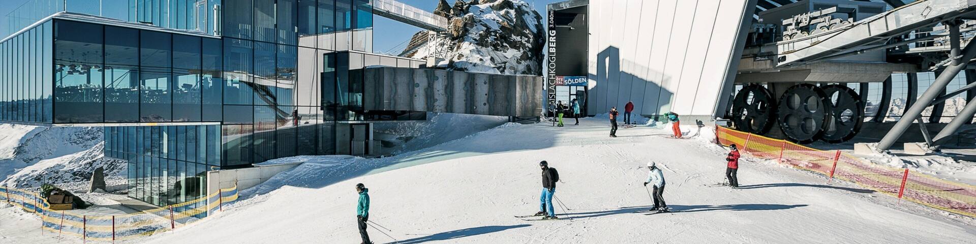 A ski resort with modern buildings, a ski lift, and skiers on the slopes.