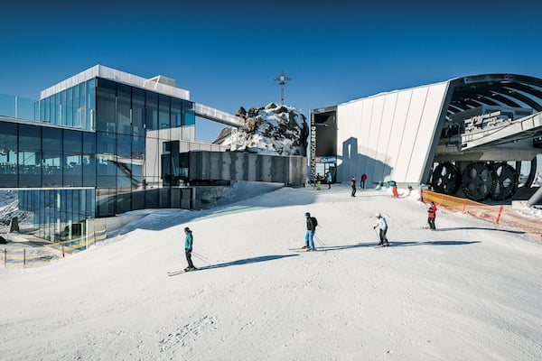 Ein Skigebiet mit modernen Gebäuden, einer Seilbahn und Skifahrern auf den Pisten.