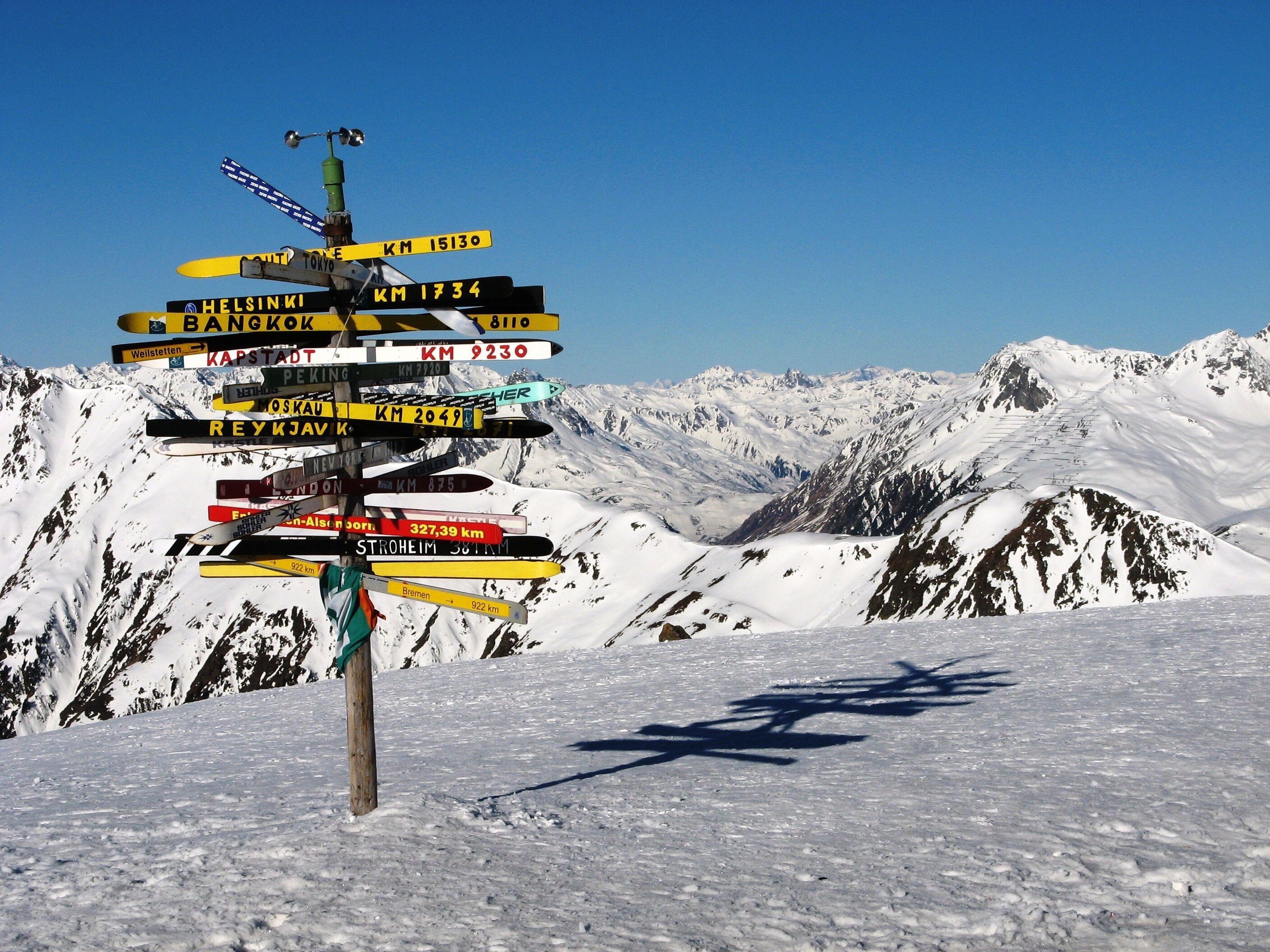 A snow-covered mountain with a signpost indicating distances to various cities.