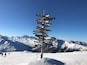 Une chaîne de montagnes enneigée, avec un panneau indicateur comportant de nombreuses flèches directionnelles.