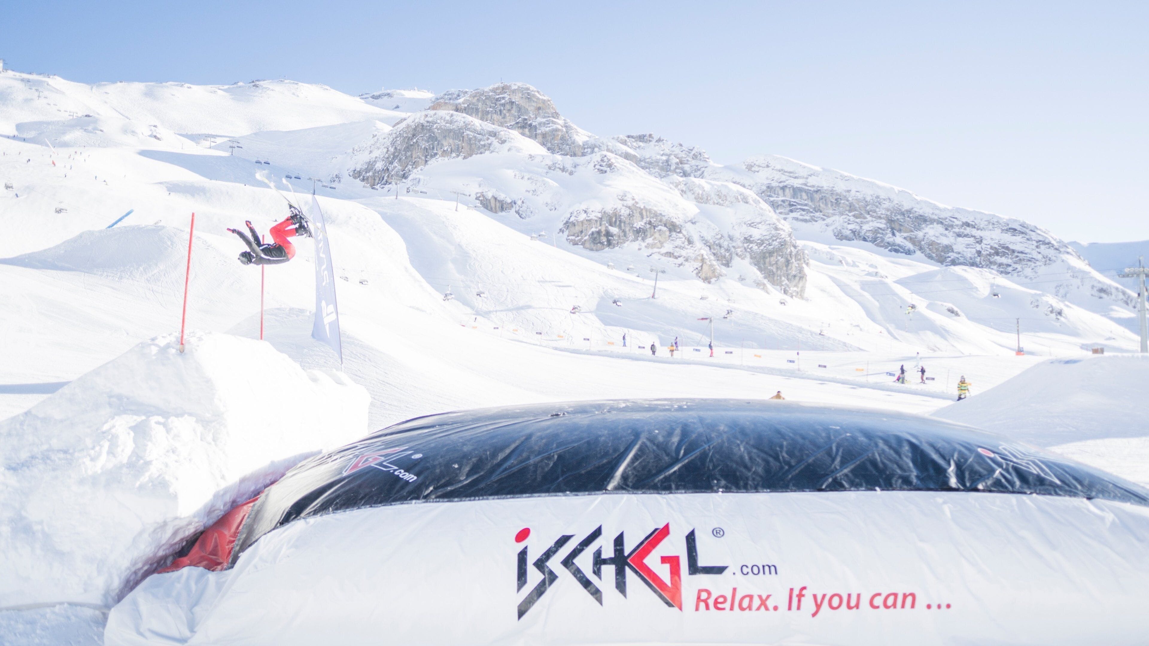A snowboarder performing a trick on a snowy mountain slope with a ski lift in the background.
