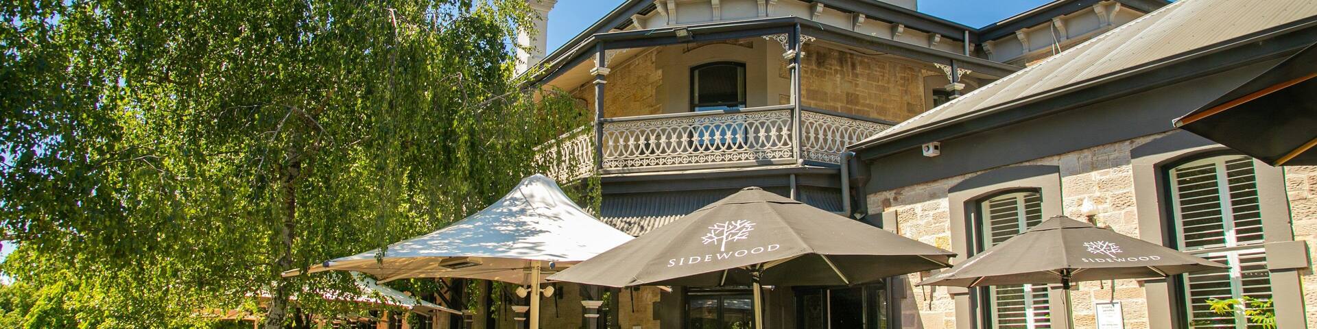 A courtyard with outdoor seating, umbrellas, and a building with a balcony.