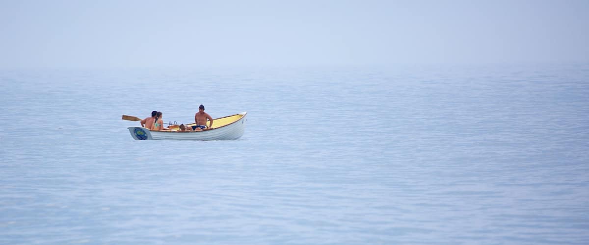 A small boat with two people on a calm sea.