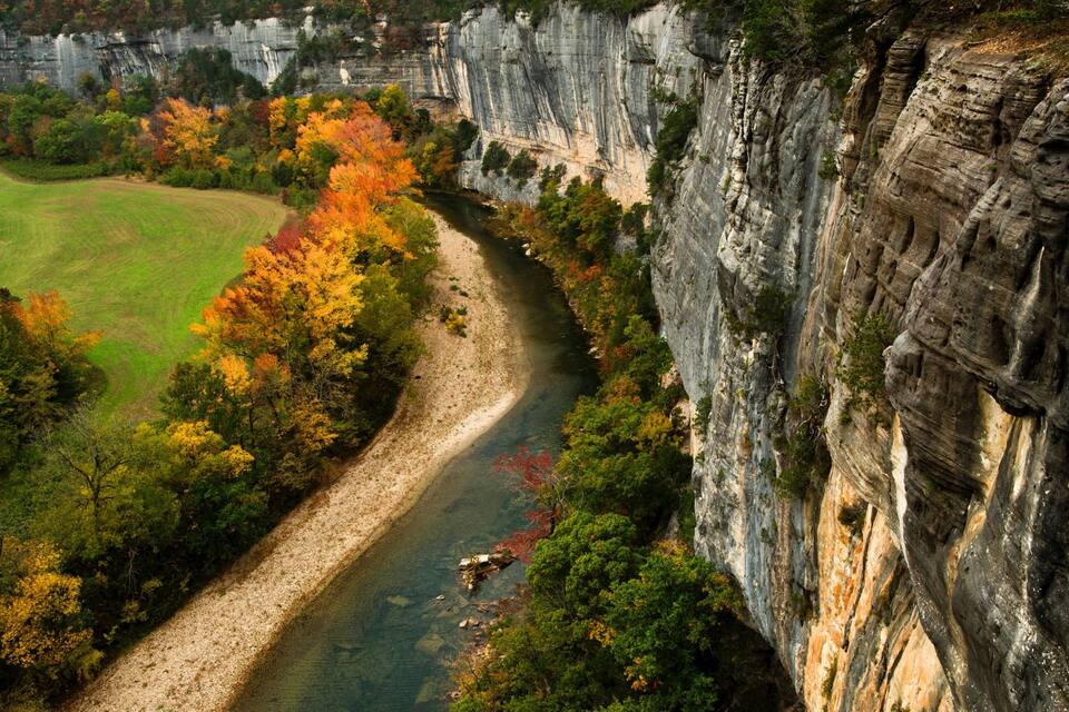 A river winding through a valley with autumn-colored trees and a steep cliff.