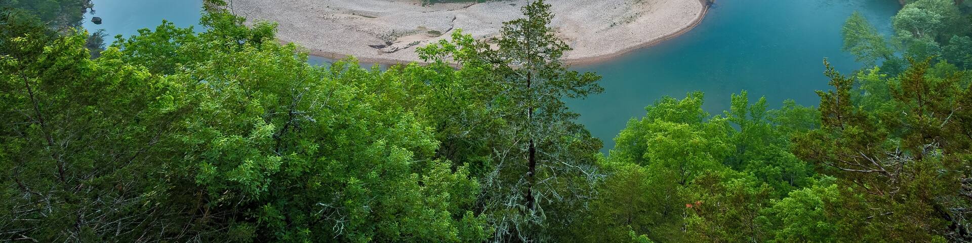 A river winding through a forested valley with a sandy island in the center.