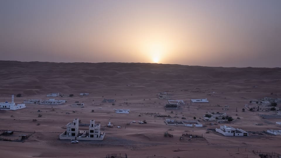 A desert landscape with scattered buildings and a prominent white structure in the foreground.