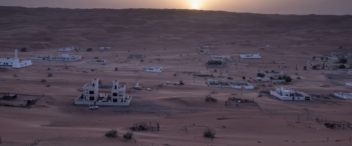 A desert landscape with scattered buildings and a prominent white structure in the foreground.