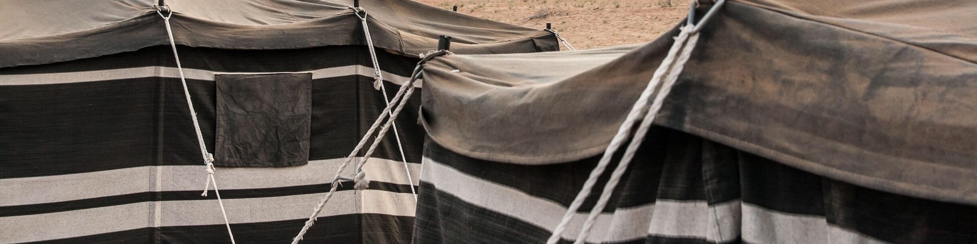 A desert landscape with tents and sand dunes.