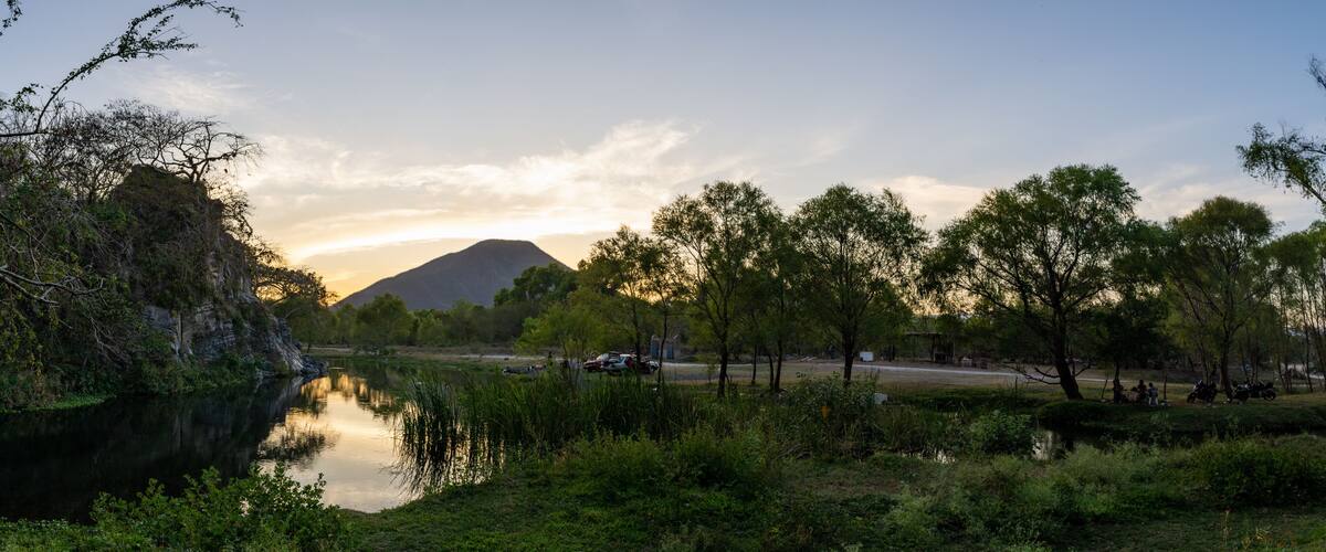 A river with trees and a mountain in the background.