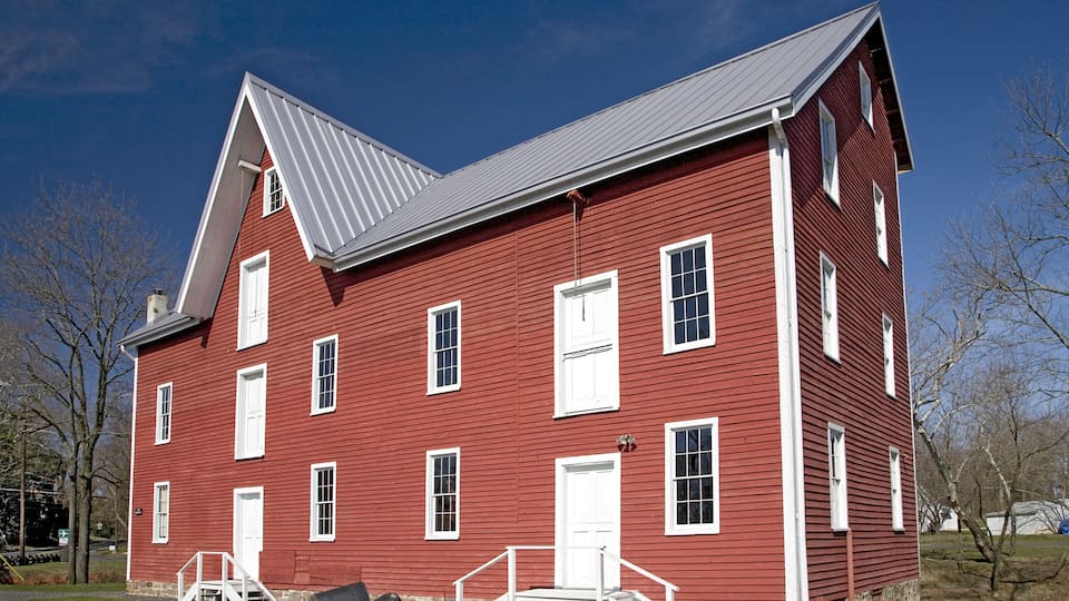 A red wooden house with white trim and a grey roof.