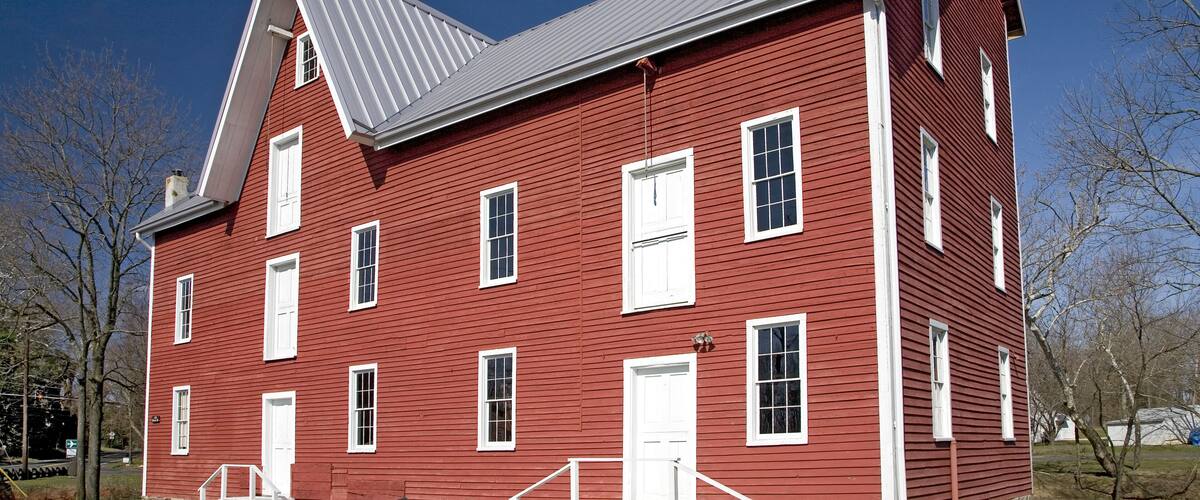A red wooden house with white trim and a grey roof.