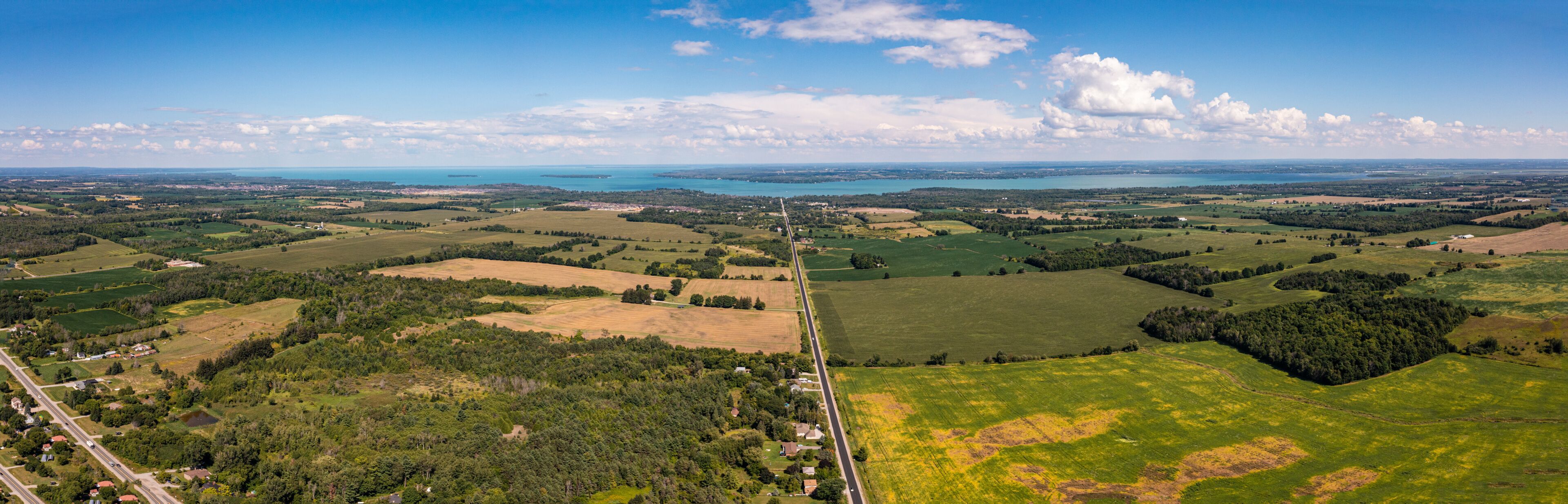 A panoramic view of a coastal landscape with rolling hills, fields, and a distant body of water.