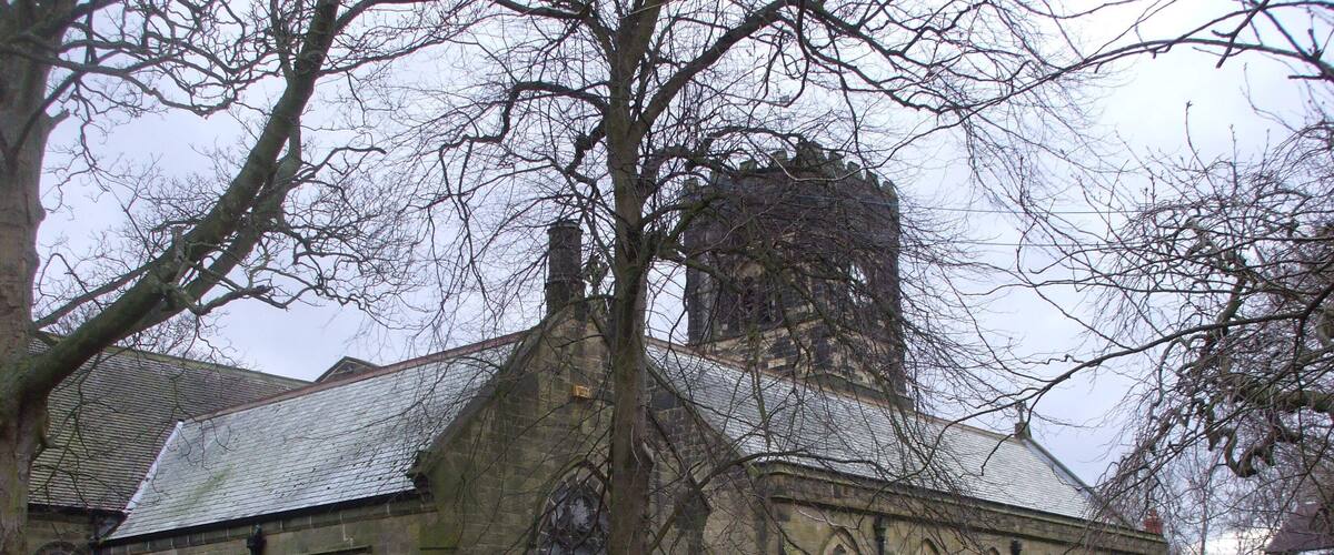 A historic church with a tall tower, arched windows, and a surrounding graveyard.