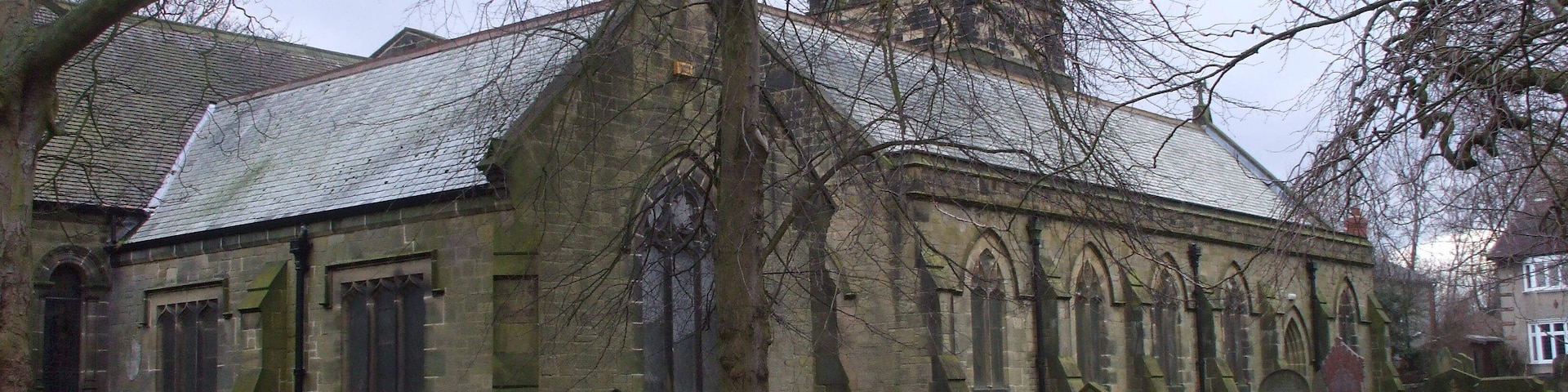A historic church with a tall tower, arched windows, and a surrounding graveyard.
