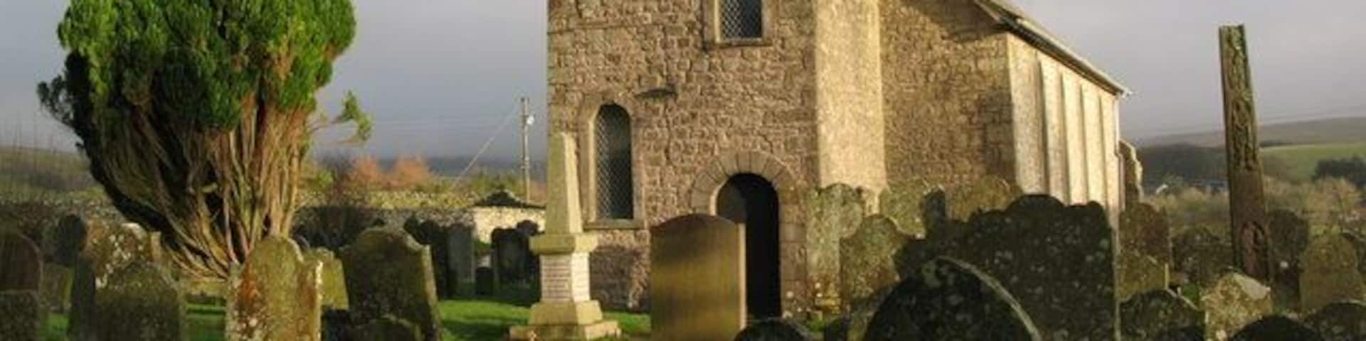 The tower of St. Cuthbert's Bewcastle, and the 7th C Cross, near to Bewcastle, Cumbria, Great Britain. See <a href="https://www.geograph.org.uk/photo/1833362">NY5674 : St. Cuthbert's Church Bewcastle, and 7th C Cross</a>.