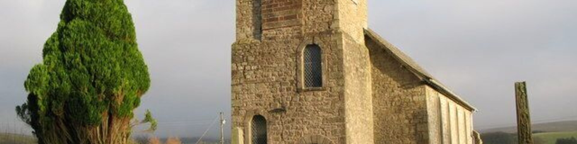 The tower of St. Cuthbert's Bewcastle, and the 7th C Cross, near to Bewcastle, Cumbria, Great Britain. See <a href="https://www.geograph.org.uk/photo/1833362">NY5674 : St. Cuthbert's Church Bewcastle, and 7th C Cross</a>.
