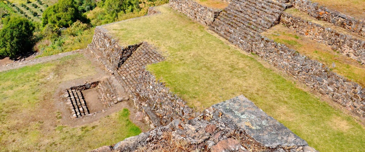 Ancient stone ruins with stepped terraces and a small courtyard.