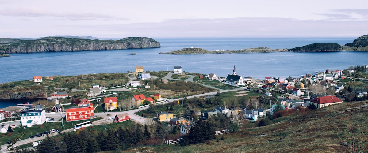A coastal town with a lighthouse, church, and various buildings.