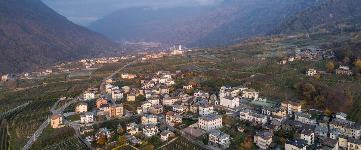A town nestled in a valley with vineyards, surrounded by mountains.