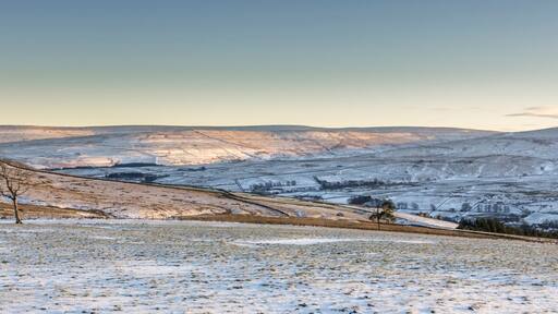 A snow-covered landscape with rolling hills and a clear sky.