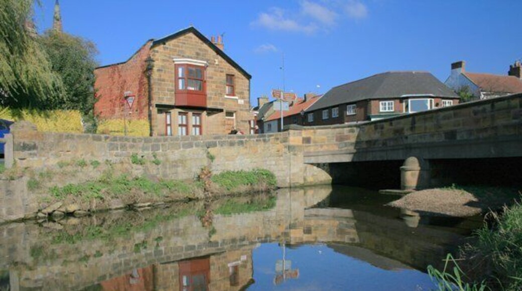The Stone Bridge Carrying the A173 through the village, bridge was built in 1909 replacing an earlier one dating from the late eighteenth century. The building reflected in the River Leven was formerly the Temperance Hotel. Opposite was Worthy Pearsons, the newsagents (first floor only visible above the bridge parapet).