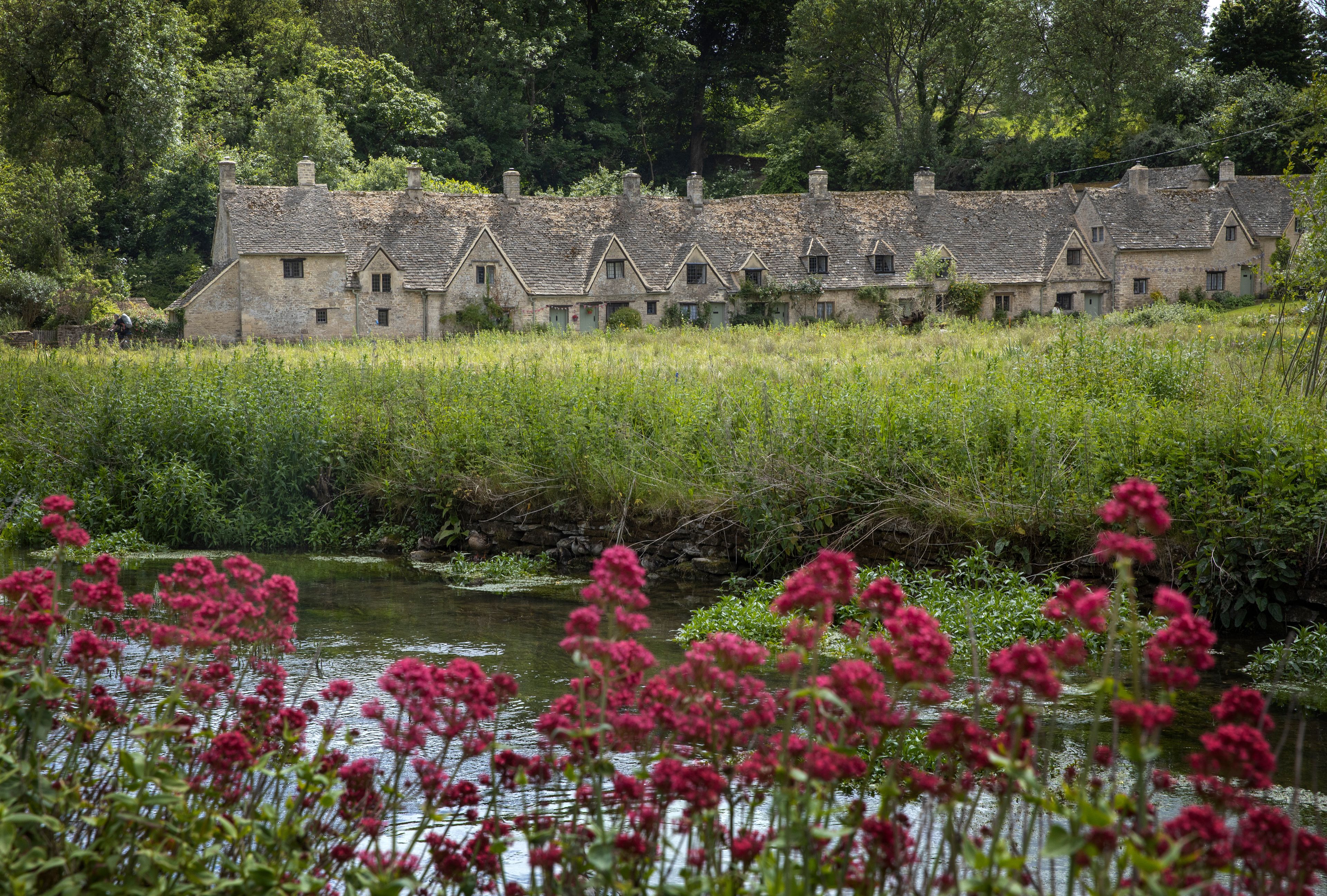 A row of stone cottages with a river in the foreground.