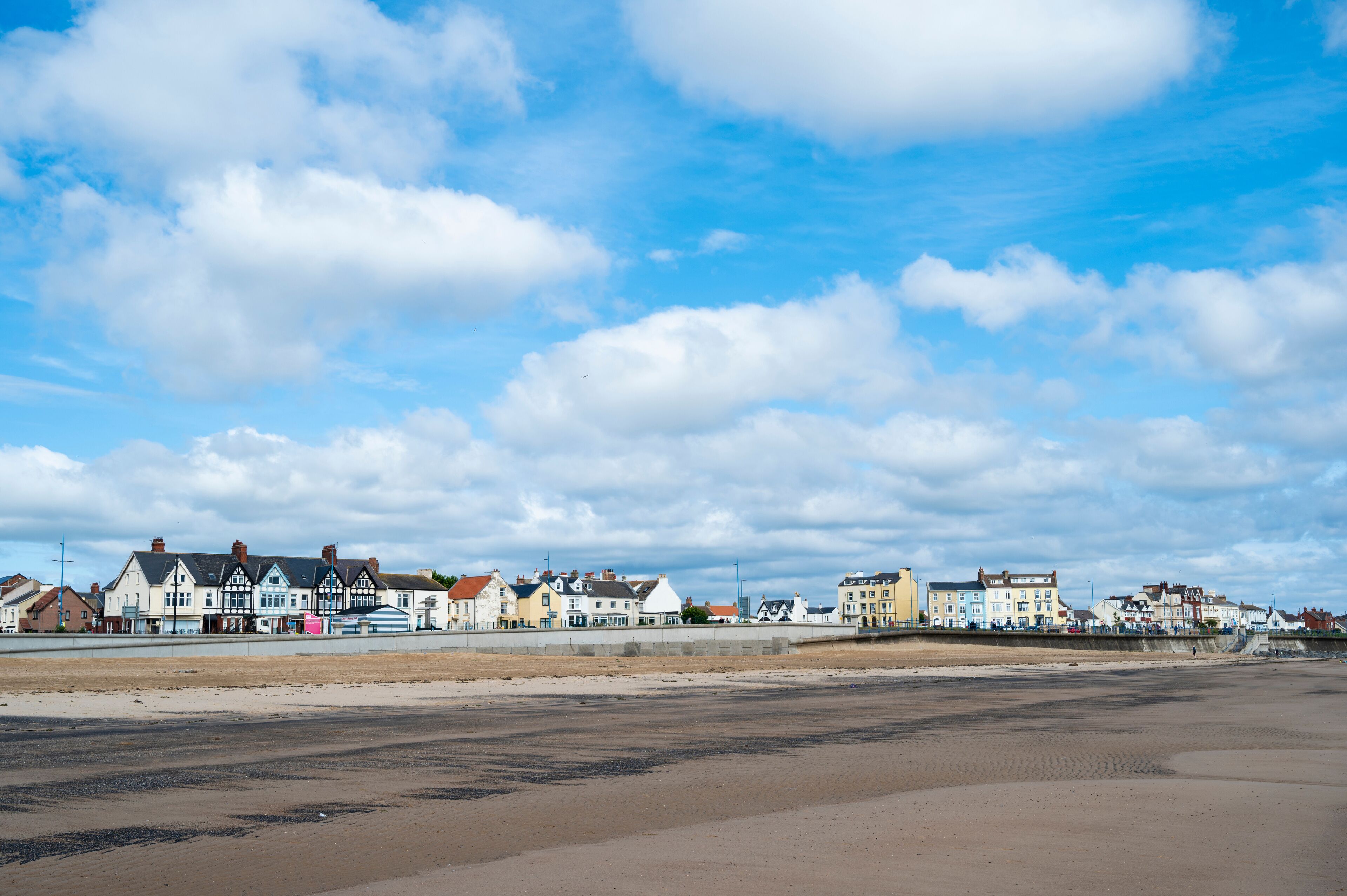 A coastal town with colorful buildings along the beach under a partly cloudy sky.