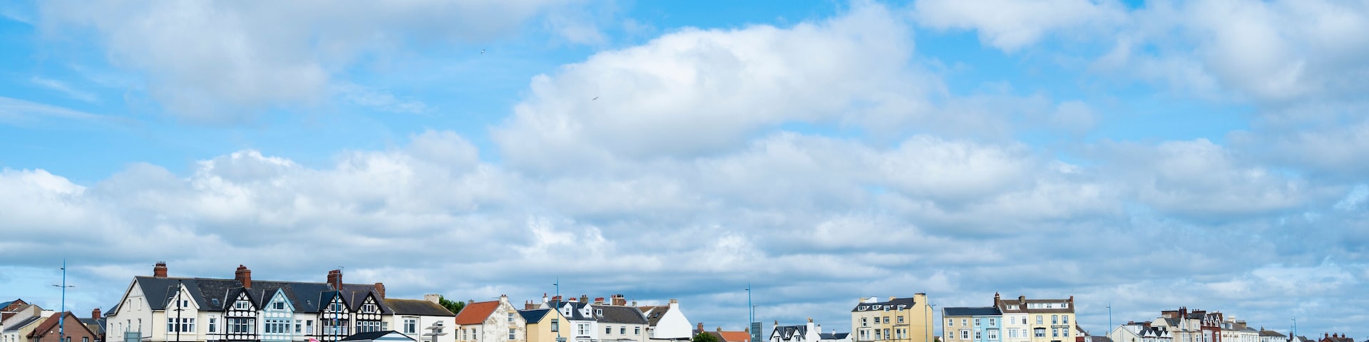 A coastal town with colorful buildings along the beach under a partly cloudy sky.
