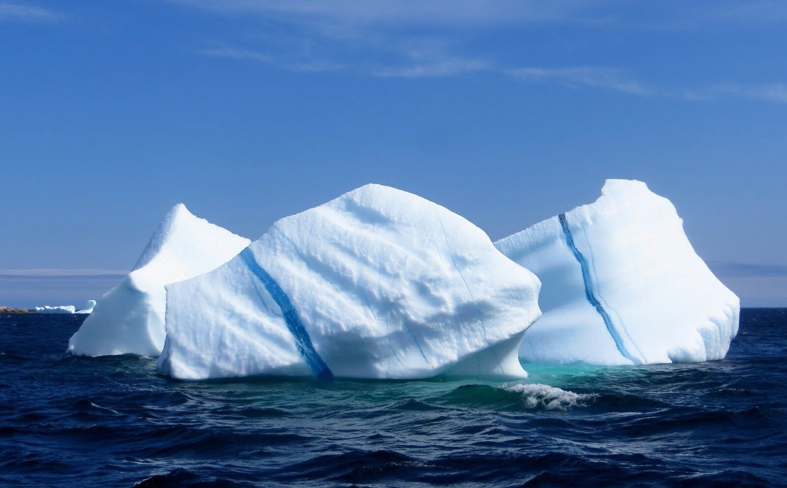 Three large icebergs floating in the ocean.