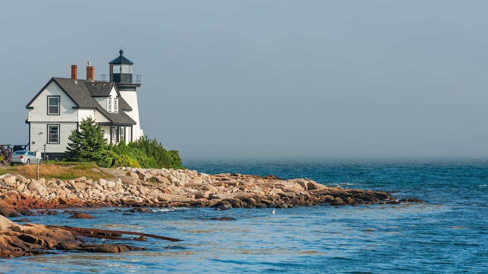A lighthouse on a rocky shoreline with calm blue waters.