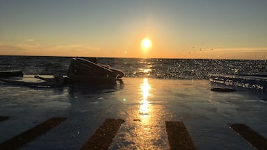 A sunset over the ocean with a boat and a buoy on the water.