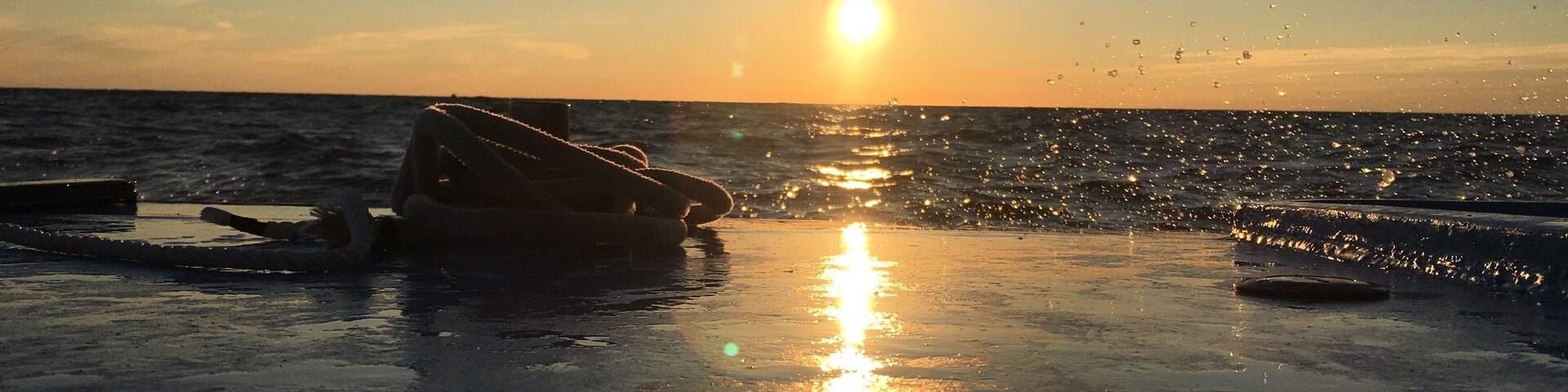 A sunset over the ocean with a boat and a buoy on the water.