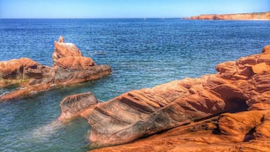 A coastal landscape with rocky formations and clear blue sea.