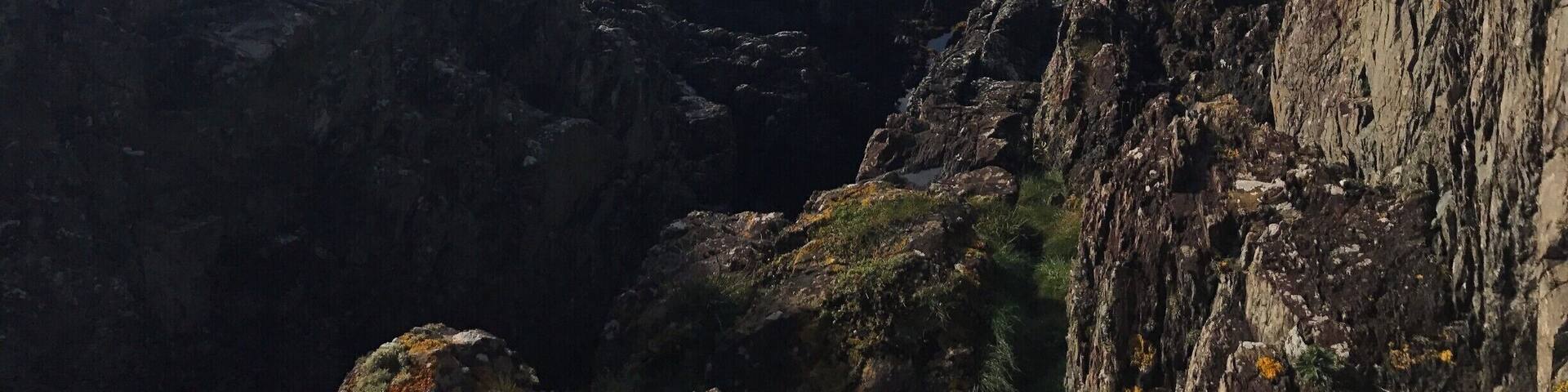 A lonely fisherman in his boat sheltered by the crags.