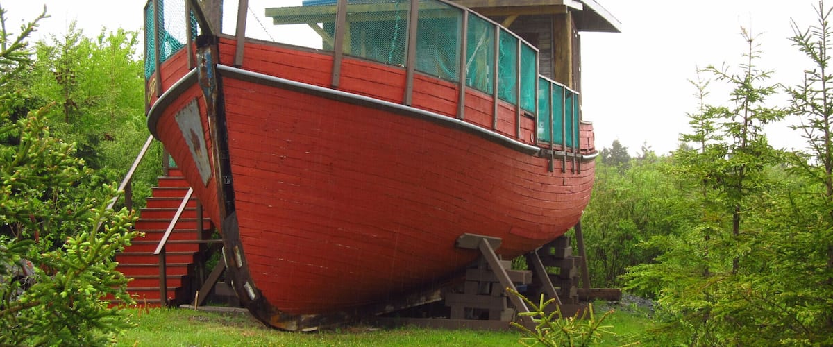 A red boat with a cabin, surrounded by greenery.