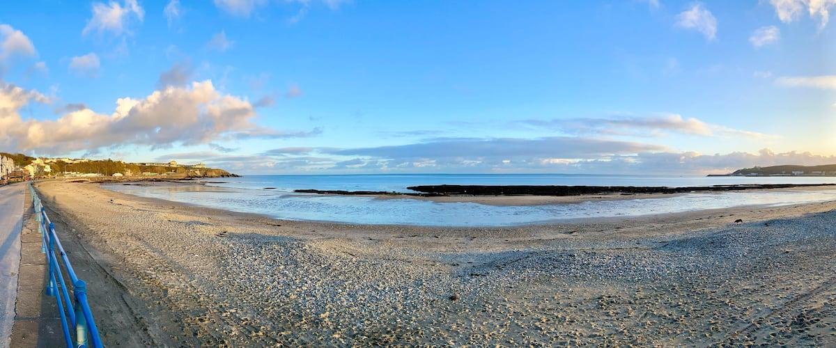 A pebble beach with a road and buildings on the left.