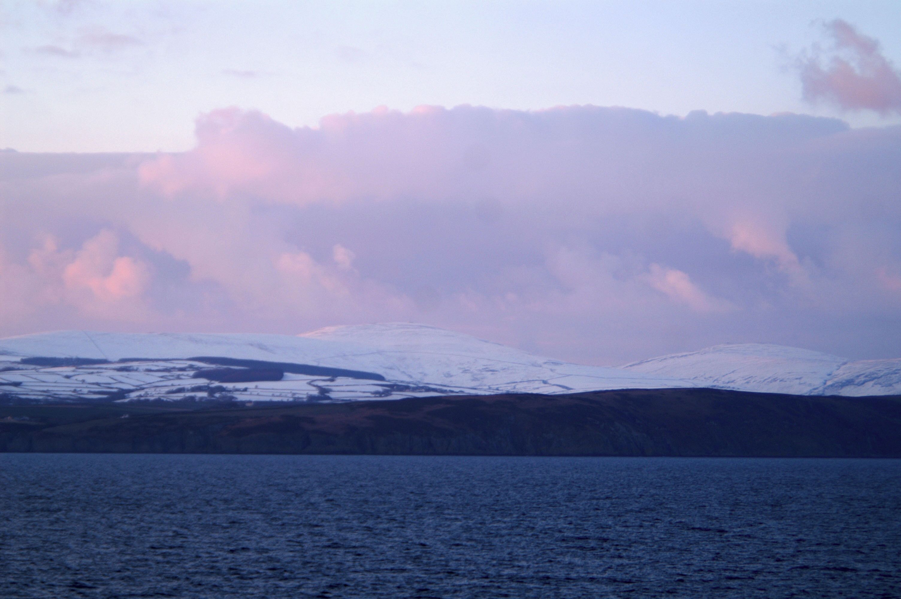 Sunset rays redden the snow on Snaefell, beyond Onchan Head From the BEN-MY-CHREE approaching Douglas