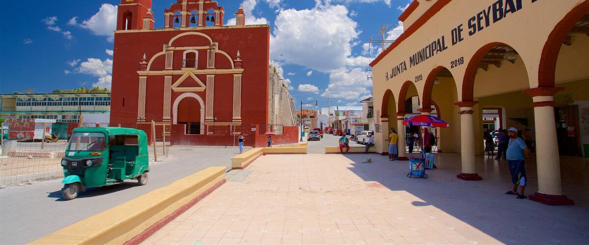 A historic church with a clock tower and a building with arches and a sign reading "H. Junta Municipal de Seybaplaya".