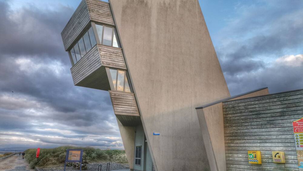A modern building with a unique angular design, featuring large windows and wooden balconies.