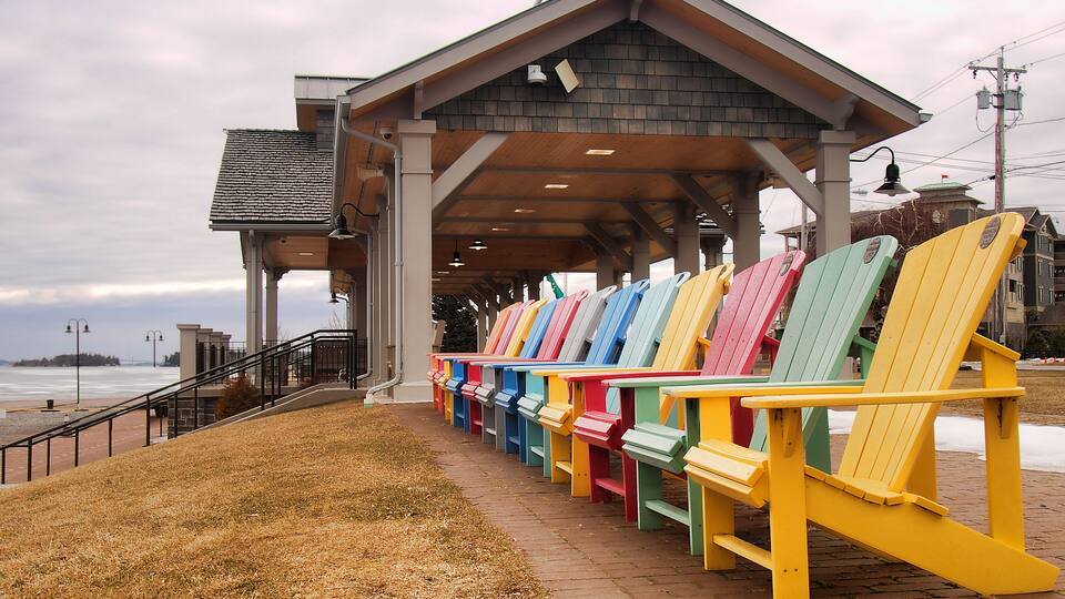 A covered seating area with colorful Adirondack chairs by the waterfront.
