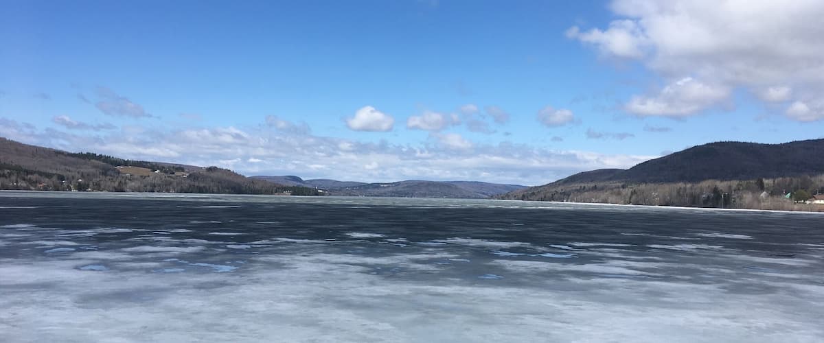 A frozen lake with mountains in the background and a clear sky.