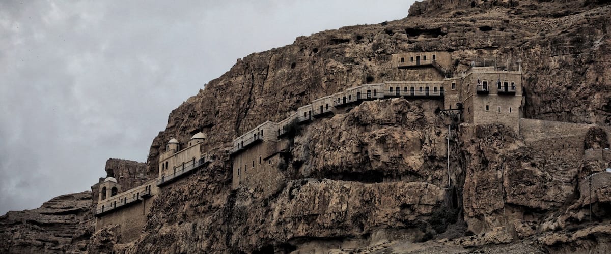 A stone staircase ascending a rocky mountain, leading to a building with domed structures.