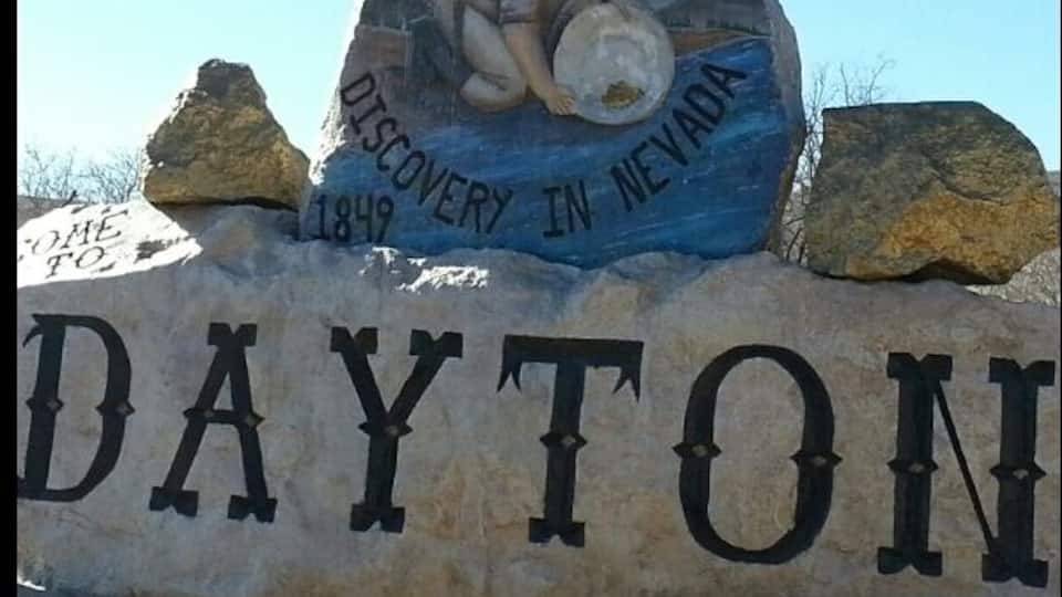 A rock with 'DAYTON' and '1849' engraved, and a painting of a man with a shield.