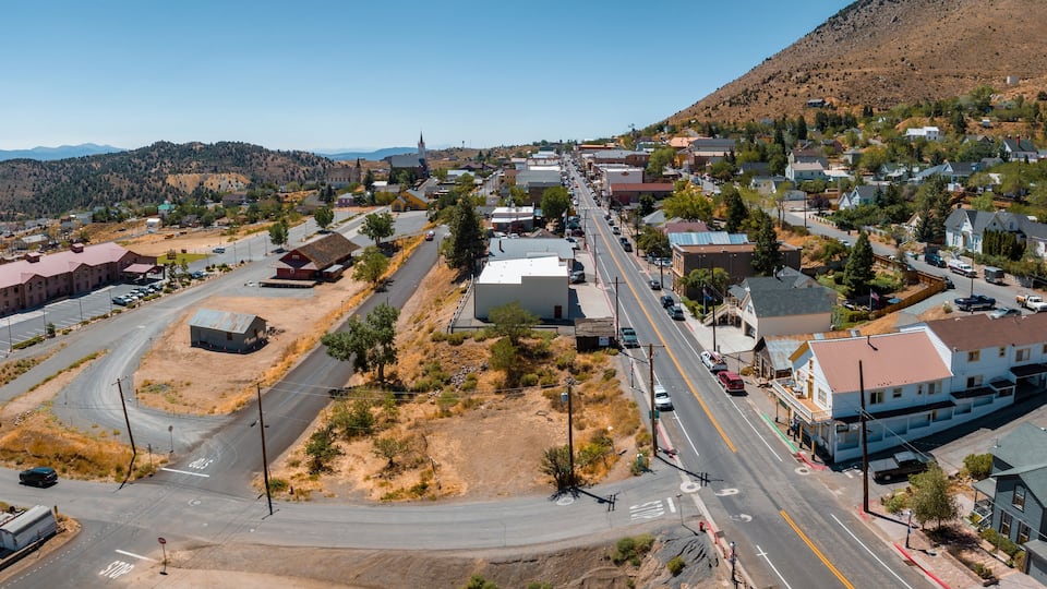 A town with a main street, buildings, and a hilly landscape in the background.