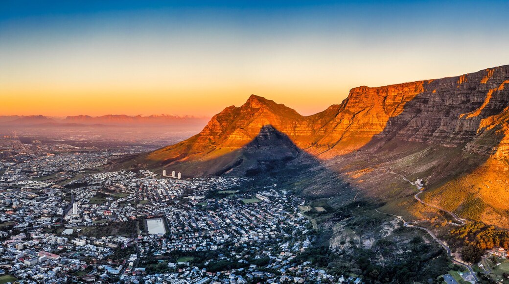 cape town aerial panorama from the table mountain at sunset, sun shining on the mountain range town in the dusk