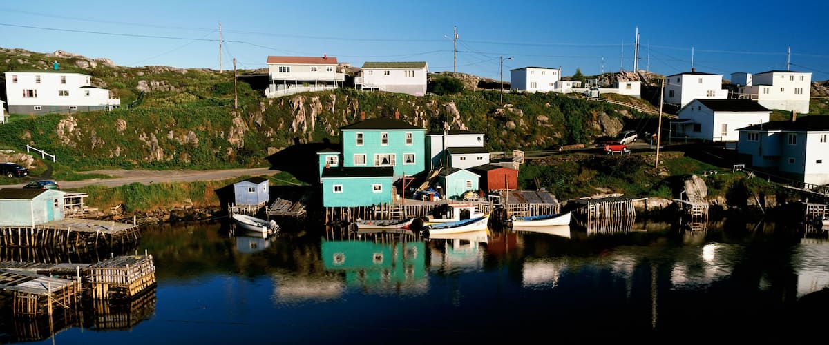 A coastal village with houses on stilts, boats docked at the pier, and a clear blue sky.