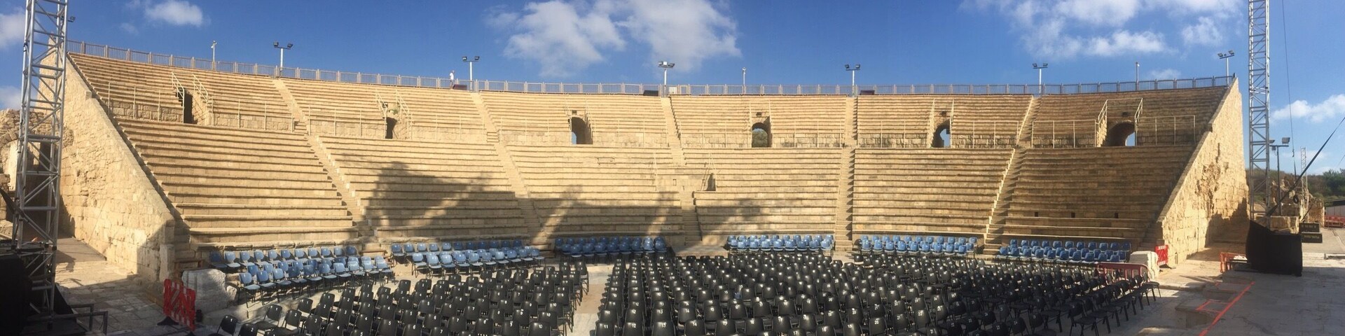 An ancient amphitheater with stone seating and a clear sky.