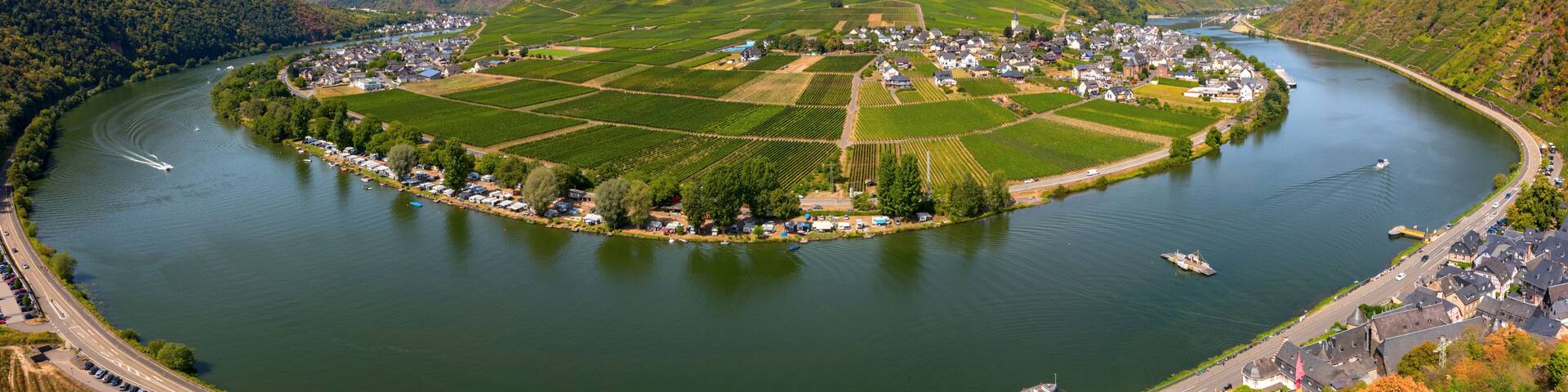 A river curving through a town surrounded by vineyards and hills.